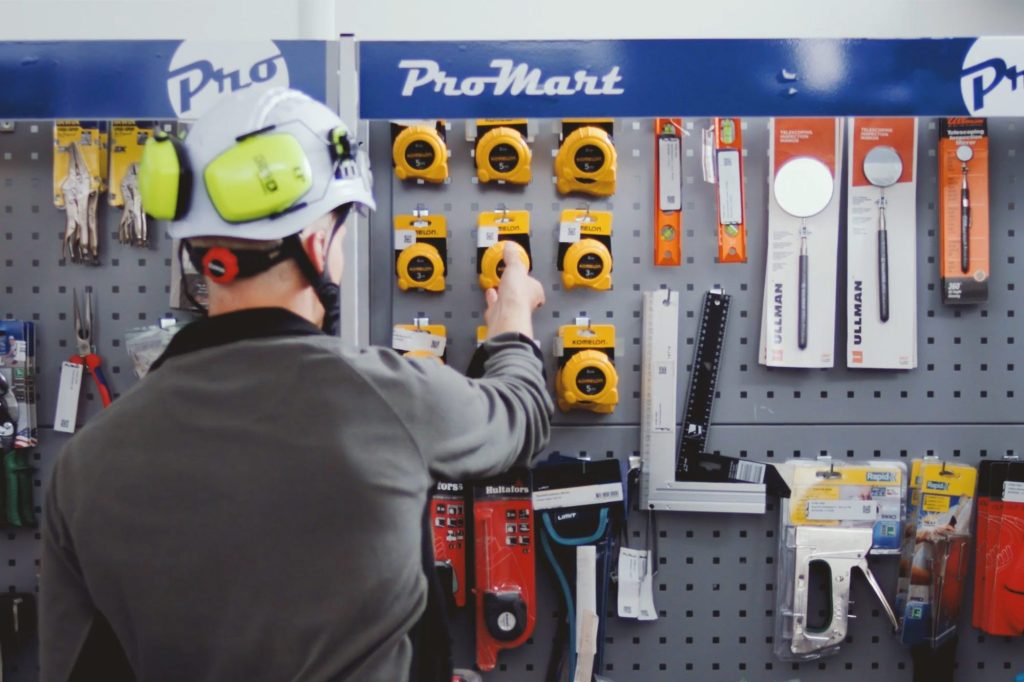 A person from behind in front of a hardware shelf in RFID enabled self-service store