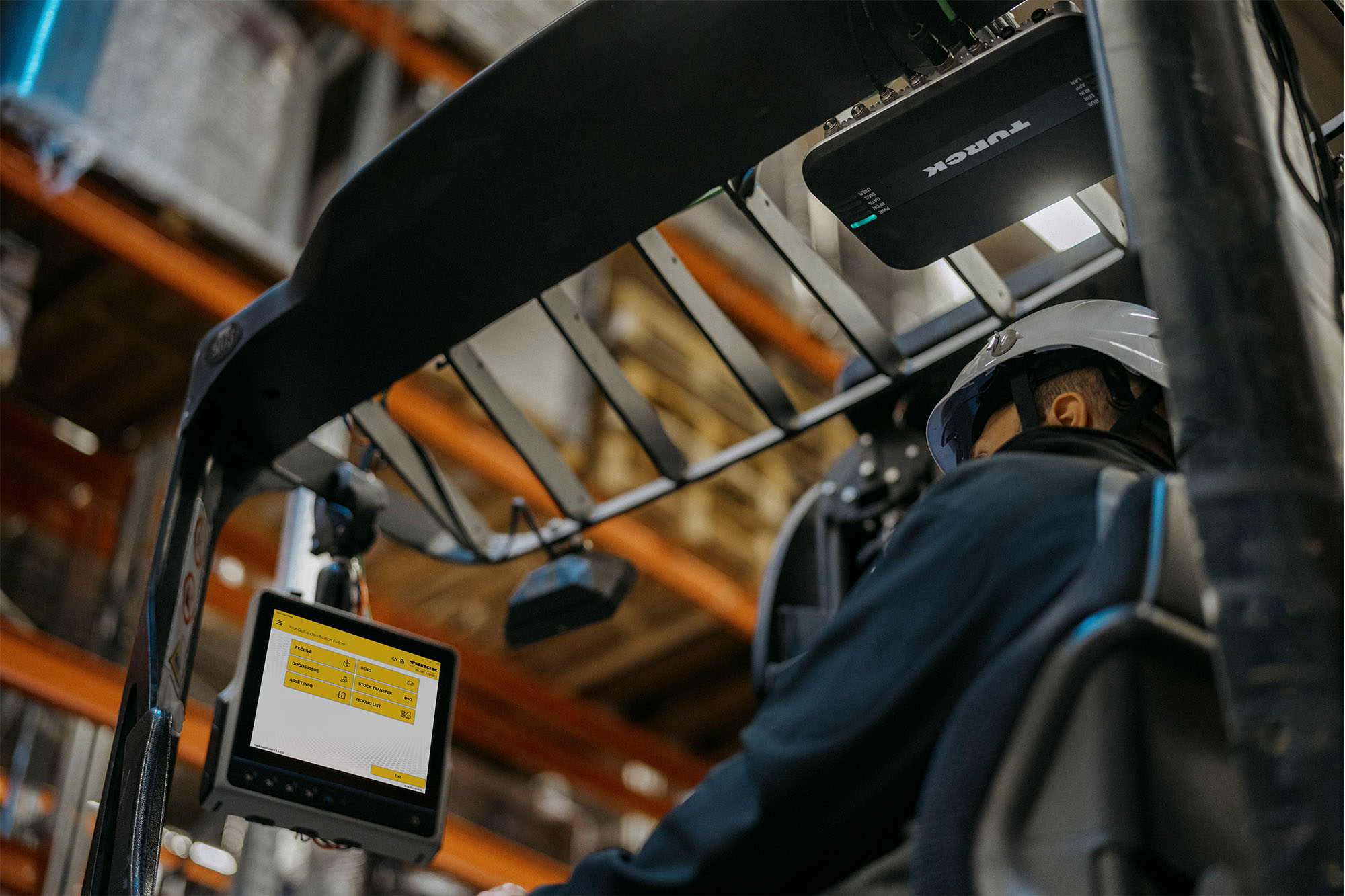 A person drives a forklift - we do not see their face, but we see a forklift PC with an application and an RFID reader on the roof