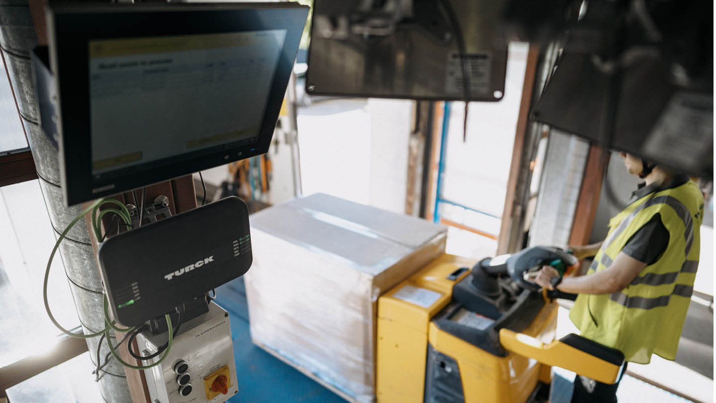 Person loading a shipment with a pallet truck and RFID equipment ensuring shipment accuracy.