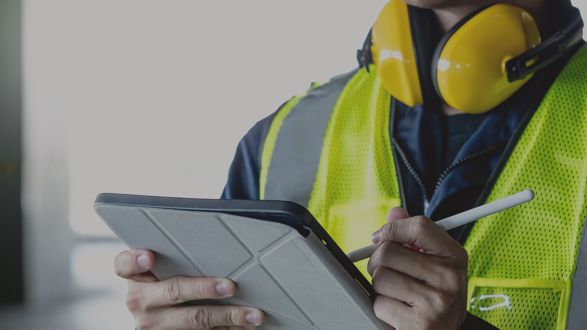 Person in Arbeitskleidung hält ein Tablet und überprüft eine Checkliste zur RFID-Systemprüfung.
