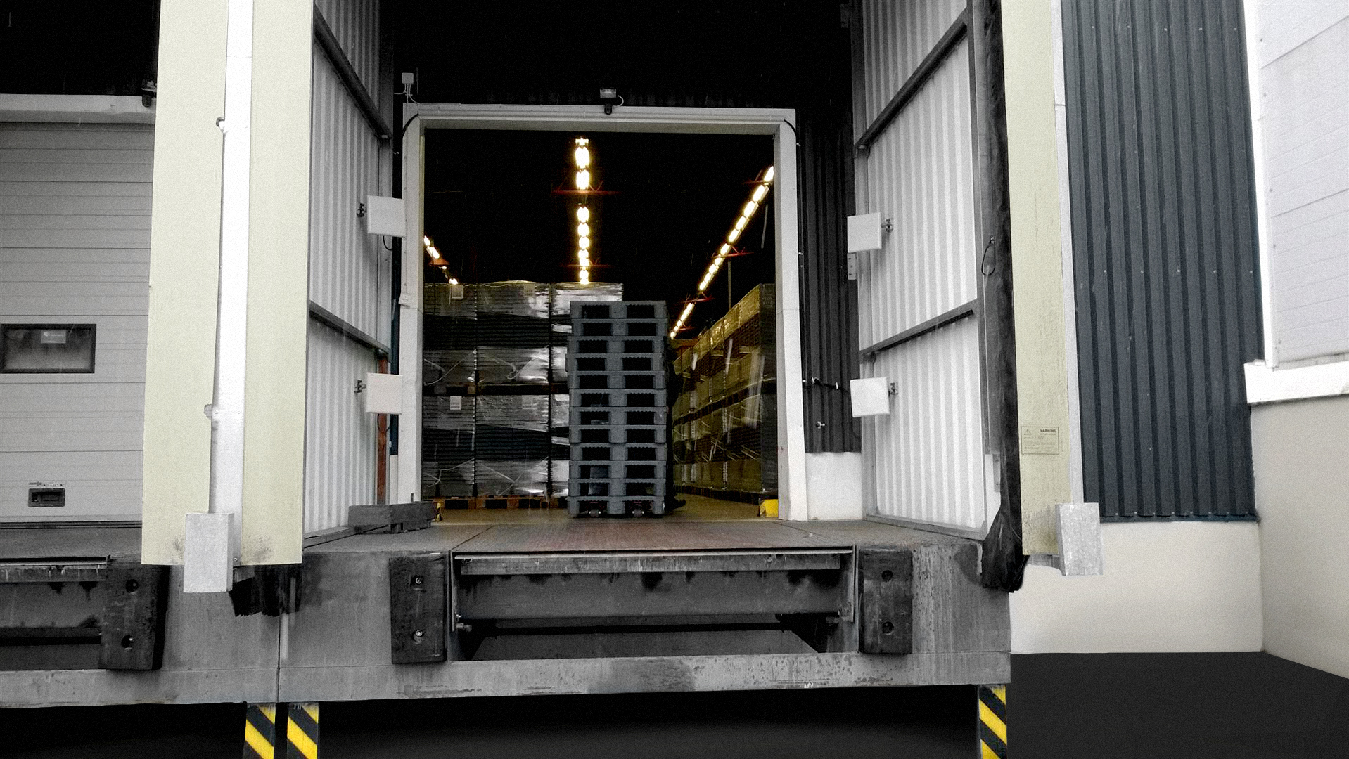 A picture of a dock door, where we see piles of plastic crates and RFID antennas