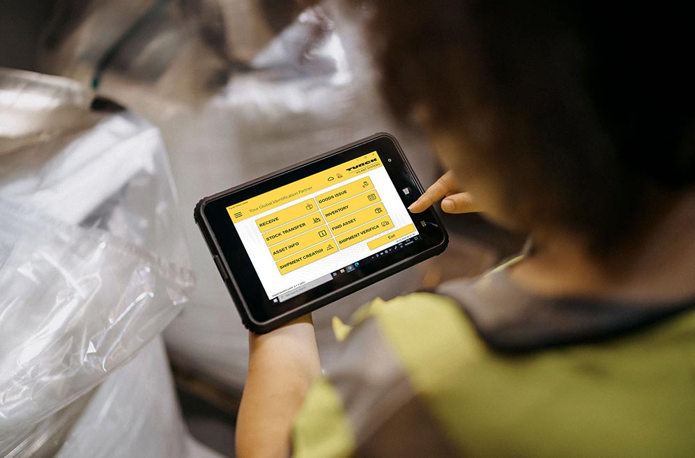 Looking over a shoulder of a person using a tablet computer in a warehouse setting