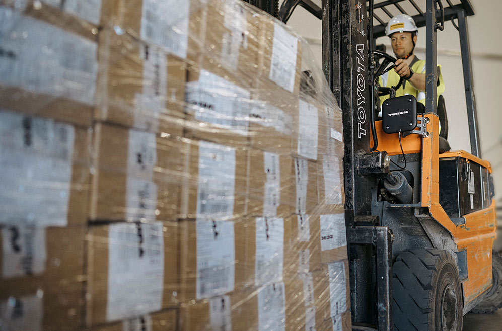 A forklift truck with a shipment of boxes, person driving, RFID antennas and RFID software registering shipment