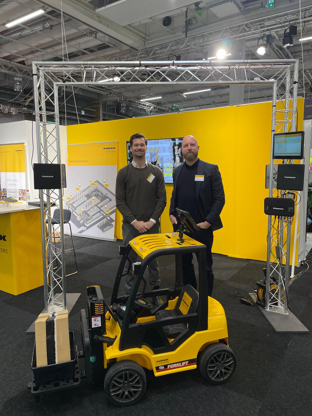 Johan Magnil and Peter Åsen of Turck Vilant Systems at the Logistics & Transport fair behind a mini forklift and inside the RFID gate