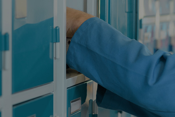 A hand taking an item from a locker in industrial environment depicting smart lockers