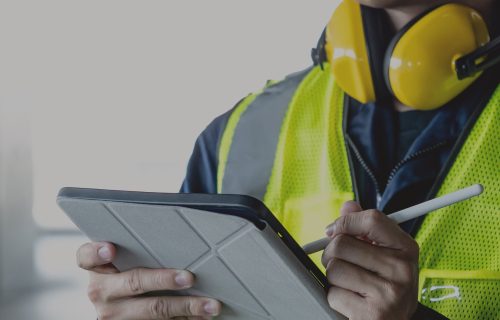 RFID-system-audit A person in industrial work wear holding a tablet checking a list of rfid system audit