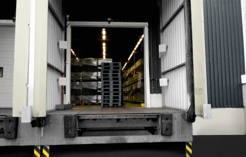 A picture of a dock door, where we see piles of plastic crates and RFID antennas